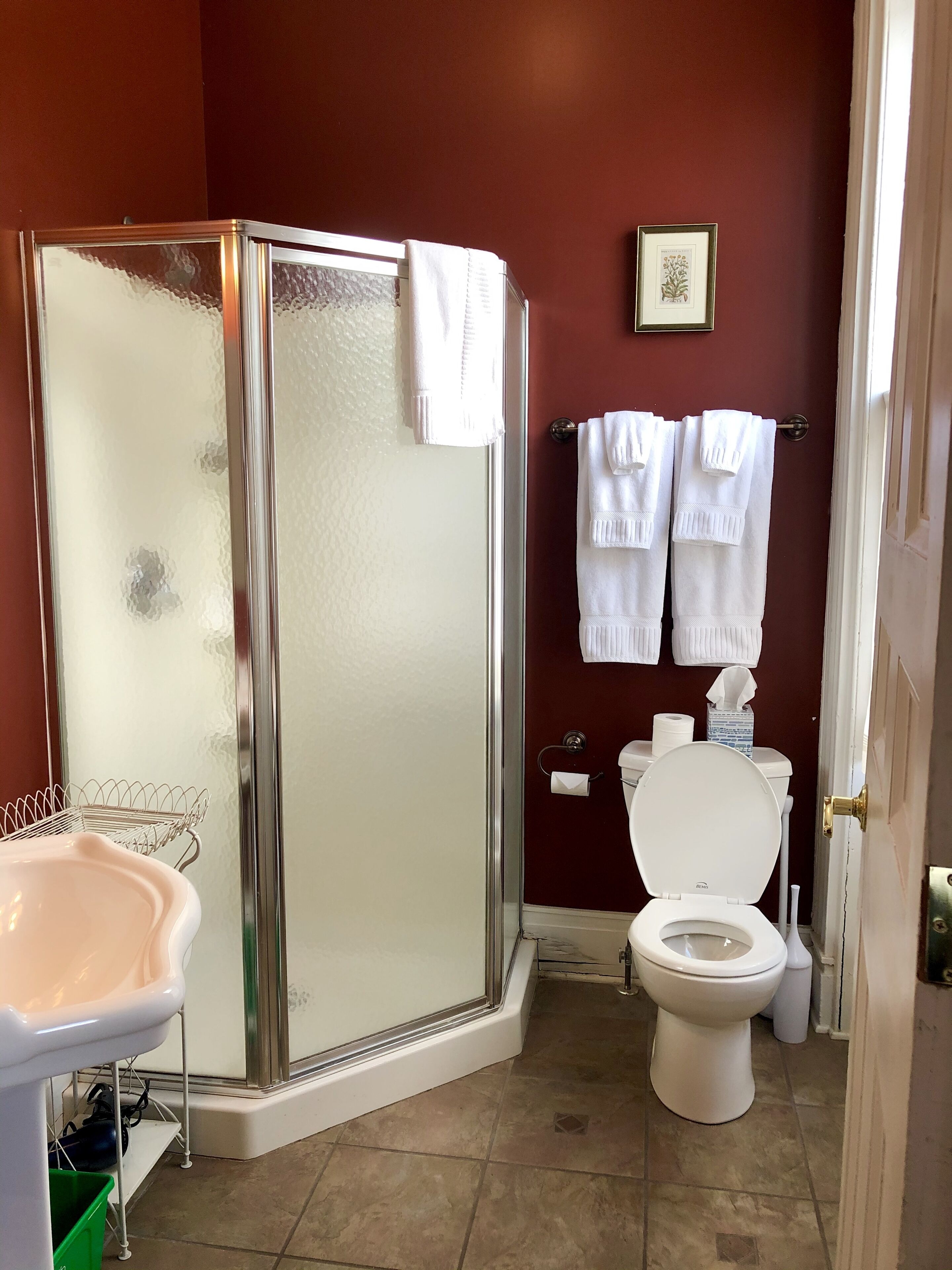 A bathroom with a glass-enclosed shower, a toilet, and a sink.