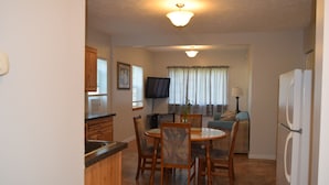 A compact kitchen with a dining area, a flat-screen TV, and a refrigerator. - Cattaraugus, Your home away from home (Cattaraugus)