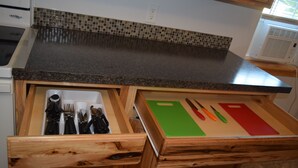 A kitchen with a granite countertop, wooden drawers, and a tiled backsplash. - Cattaraugus, Your home away from home (Cattaraugus)