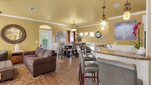 A spacious living room with a brown leather sofa, a dining area with a table and chairs, and a kitchen area with a sink and counter. - Renovated Pet Friendly Home-Private Beach Access (Destin)