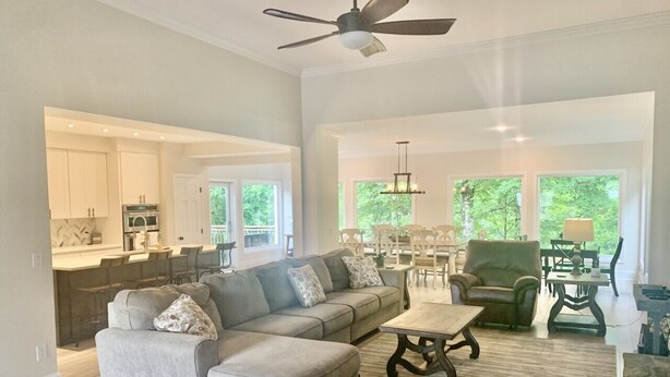 A spacious living room with a sectional sofa, a coffee table, and a dining area with chairs and a table.