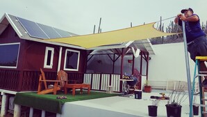 A house with a patio, a wooden deck, and a covered area with a grill.