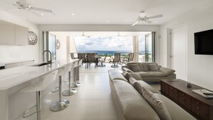 Eine moderne Küche mit Bar, einer Sitzecke inklusive Sofa und Sesseln, und Blick aufs Meer.
