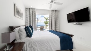 Ein Hotelzimmer mit Bett, Fernseher, Deckenventilator und Meerblick.