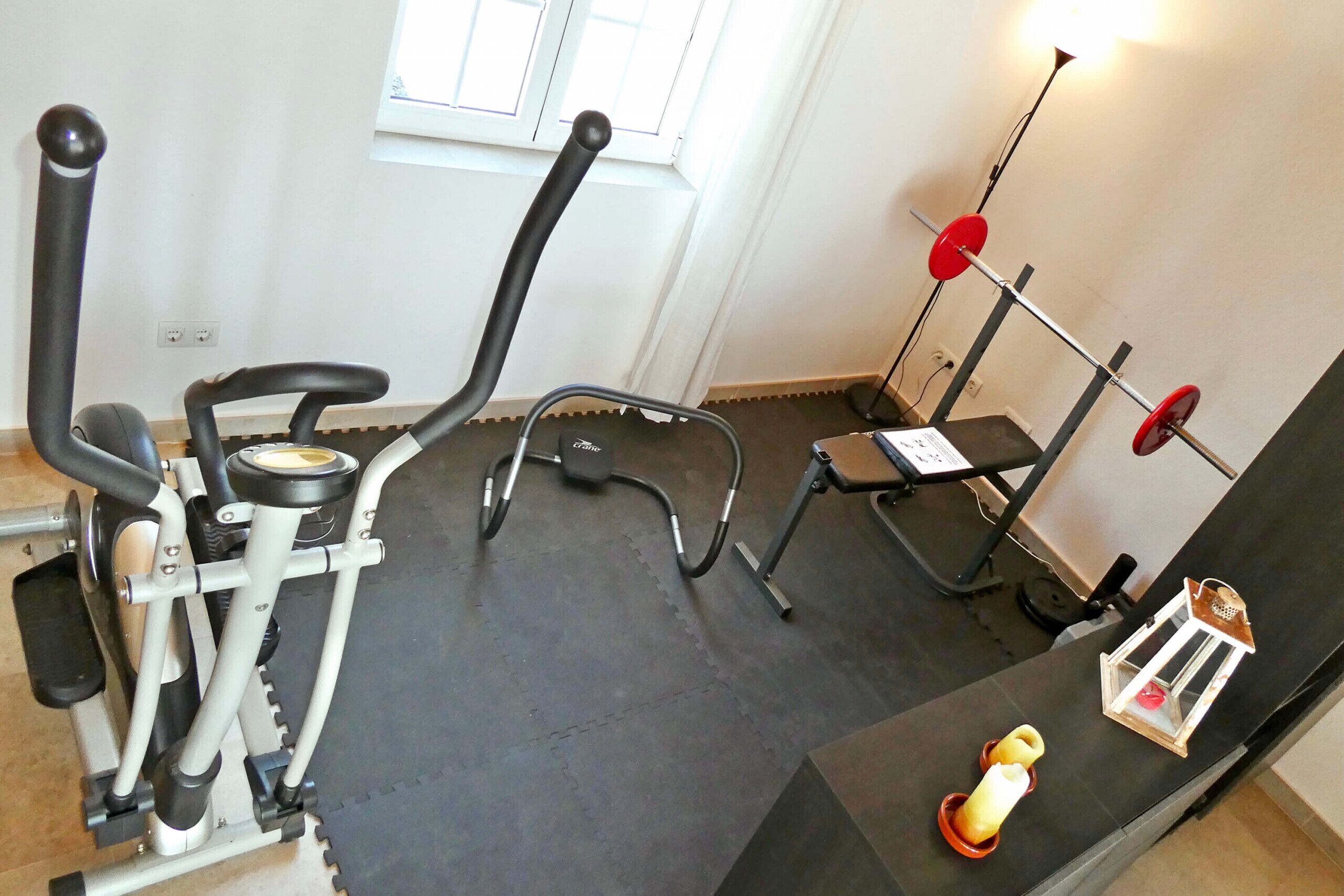 Ein Fitnessraum mit Trainingsgeräten, einem Fenster und einer Lampe.