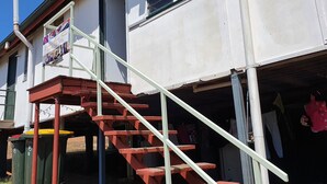 A building with a staircase leading to an upper floor, a signboard, and a window with a view of the sky. - Golden Mount Rest, 9 guest's max, 1 Double, 7 Singles  (Mount Morgan)