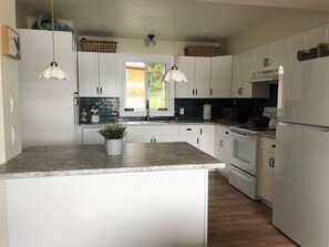 A modern kitchen with white cabinets, a central island, a built-in oven, and a refrigerator. - Gorgeous Lakefront cabin, pet friendly! (Sheridan Lake)