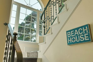 A staircase with ornate metal railings and a sign that reads 'BEACH HOUSE' on the wall.