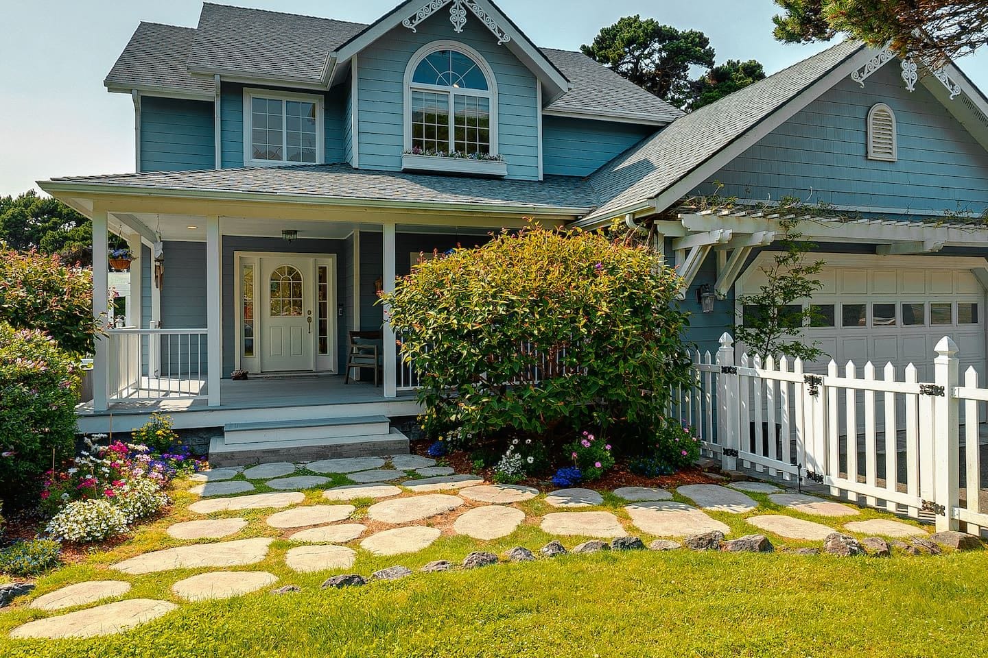 A two-story house with a porch, a garage, and a stone pathway leading to the front door.