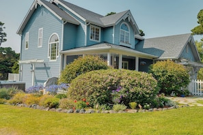A two-story house with a porch, a covered front entry, and a well-maintained garden with various plants and flowers.