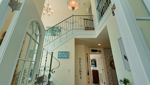 A staircase with a wrought iron railing, a 'Beach House' sign, and a 'Welcome' sign.