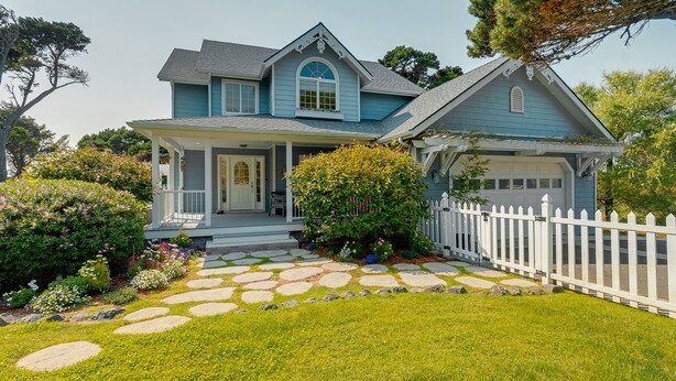 A two-story house with a porch, a garage, and a stone pathway leading to the front door.