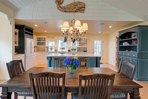 A spacious kitchen with a central island, wooden dining table, and chairs.