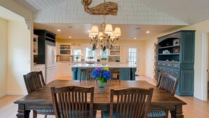 A spacious kitchen with white cabinetry, a central island, and a chandelier.