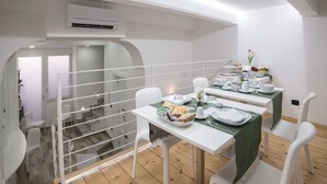 A dining area with white furniture, a green tablecloth, and a variety of dishes and drinks. - Angel's Care B&B (Reggio Calabria)