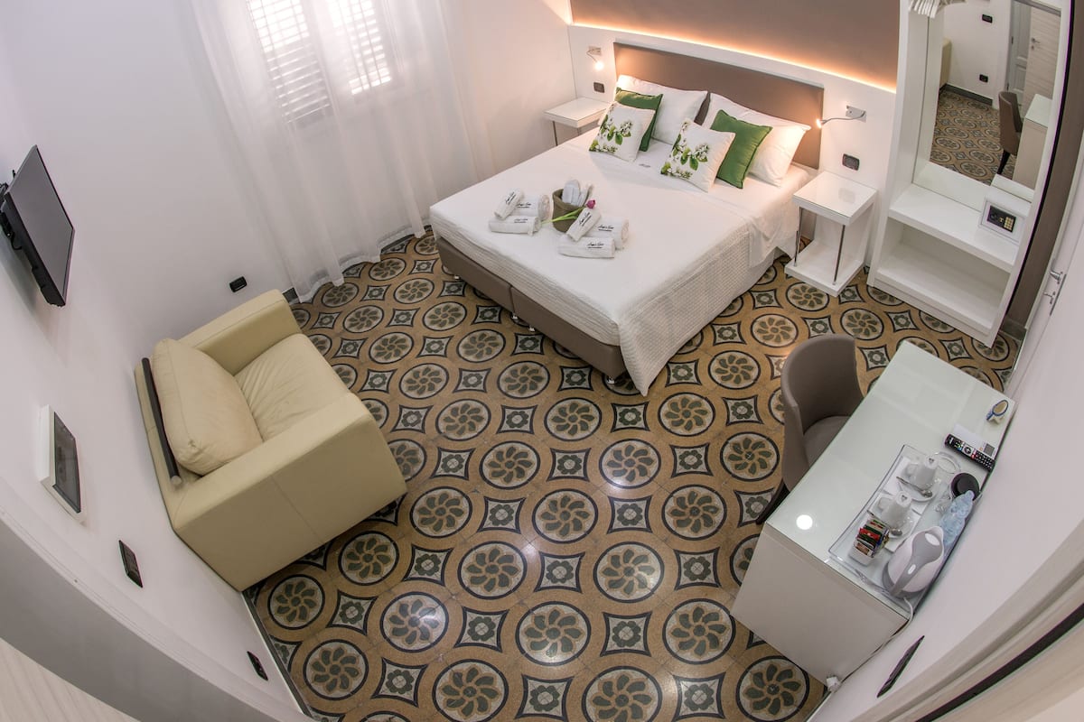 A hotel room with a bed, a sofa, a desk, a mirror, and a bathroom.