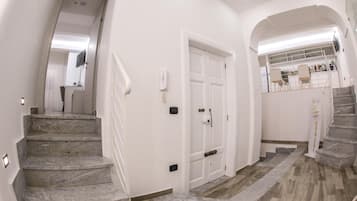 Un interior moderno con escaleras de mármol, paredes blancas y suelo de madera.