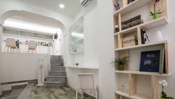 A modern interior with a staircase, a seating area, and a bookshelf with books and decorative items.