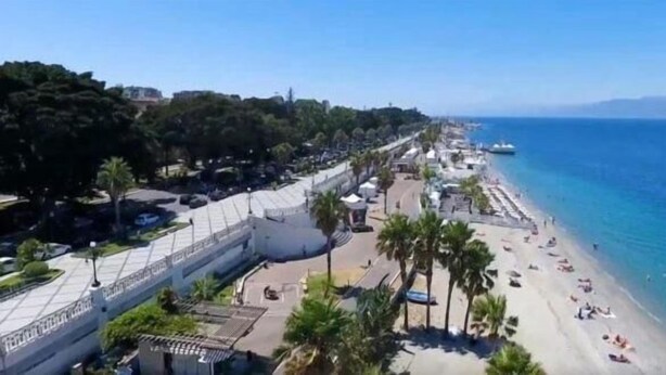 A coastal area with a beach, a promenade, and a large building with a glass facade. - Angel's Care B&B (Reggio Calabria)