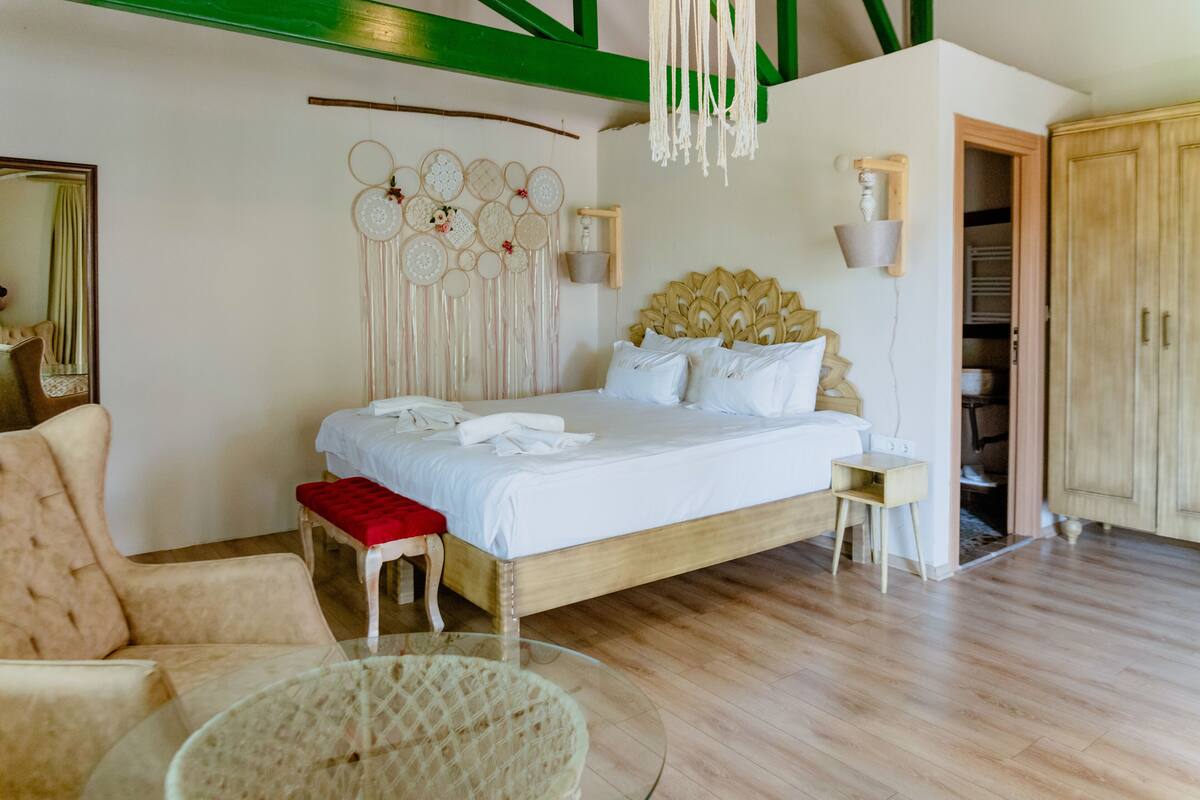 Een slaapkamer met een houten bed, een rode bank, een glazen tafel en een garderobe.