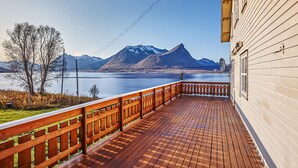 Een houten terras met uitzicht op een meer en bergen.