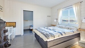 Een slaapkamer met een groot bed, een raam met uitzicht, een bureau en een stoel.