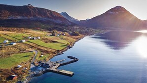 A coastal village with houses along the shoreline, a dock, and mountains in the background. - Beautiful home in Sortland with WiFi (Sortland)