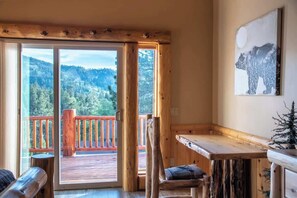 L’intérieur d’un chalet en bois, avec un balcon, un banc en bois et un tableau représentant un ours.