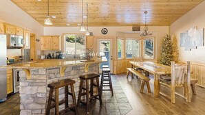 Eine Küche mit Holzausstattung, einer Steinservierplatte, Barhocker, einem Holztisch und einem Weihnachtsbaum.