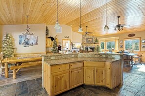 Une cuisine spacieuse avec des meubles en bois, un comptoir en granit et une cheminée en pierre.