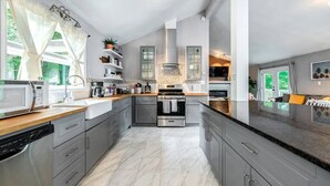 A modern kitchen with grey cabinets, a central island, stainless steel appliances, and a view of the outdoors.