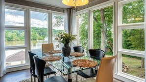 A dining area with a glass table, black chairs, and a vase of flowers.