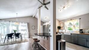 A modern kitchen with a central island, bar stools, and a ceiling fan.