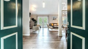A spacious living area with a wooden floor, a sofa, a coffee table, and a dining table.