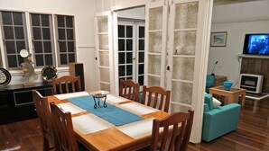 A dining area with a wooden table and chairs, a blue placemat, and a glass-top coffee table. - At the Centre of Gallery Walk, Tamborine Mountain (Eagle Heights)