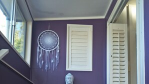 A statue of a seated figure in a room with purple walls, a dreamcatcher, and a window. - At the Centre of Gallery Walk, Tamborine Mountain (Eagle Heights)