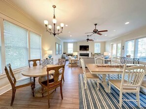 A spacious dining area with a long table and chairs, a chandelier, ceiling fans, and large windows. - Extraordinary Hilton Head Beach Home, Private Pool (Hilton Head Island)