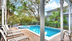 Un espace piscine avec des chaises longues, un jacuzzi et une terrasse couverte.