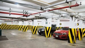 A parking garage with multiple levels, marked parking spaces, and visible structural elements like pipes and columns. - Hotel Las Lomas (Lima)