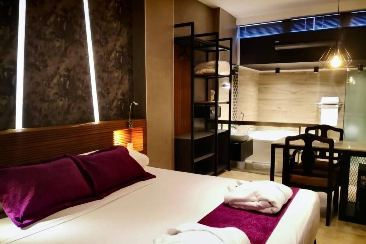 Una habitación de hotel con cama, escritorio, silla, baño y armario.