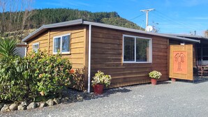 A small wooden cabin with two windows, a satellite dish, and a decorative lobster cutout on the door.