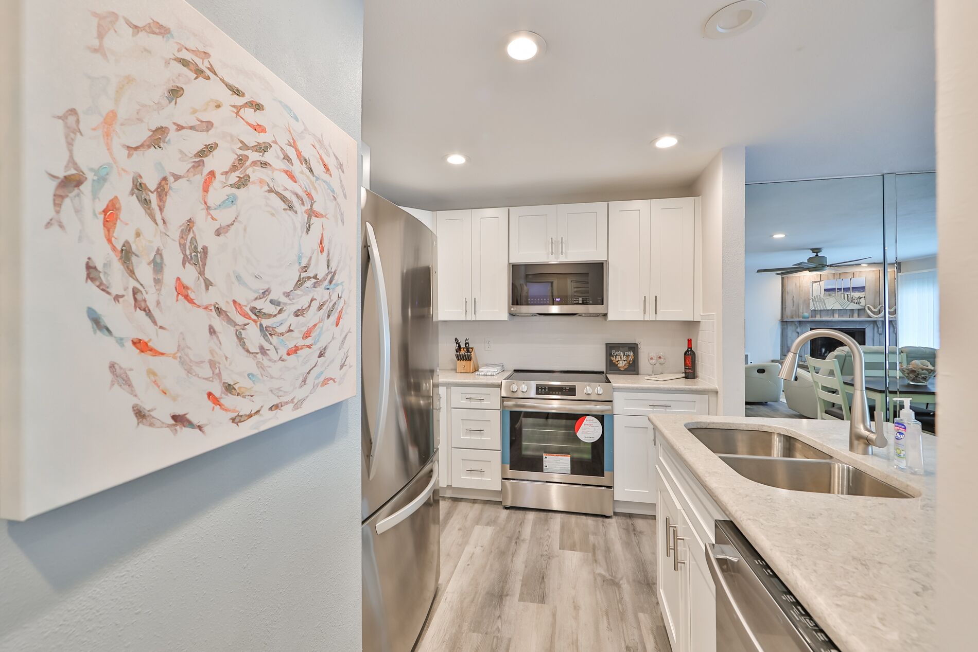 Una cocina moderna con armarios blancos, electrodomésticos de acero inoxidable y un cuadro abstracto de gran tamaño en la pared.