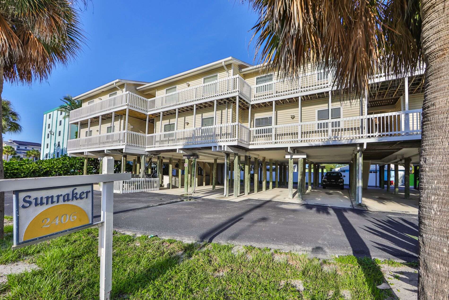 A beachfront hotel with multiple balconies and a parking area.