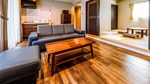 A modern living room with a sofa, a wooden coffee table, and a dining area with tatami mats. - Ahman Inn Island Yagaji (Nago)
