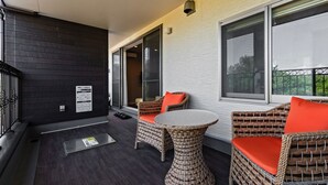 A balcony with wicker furniture, a small table, and a view of greenery. - Ahman Inn Island Yagaji (Nago)