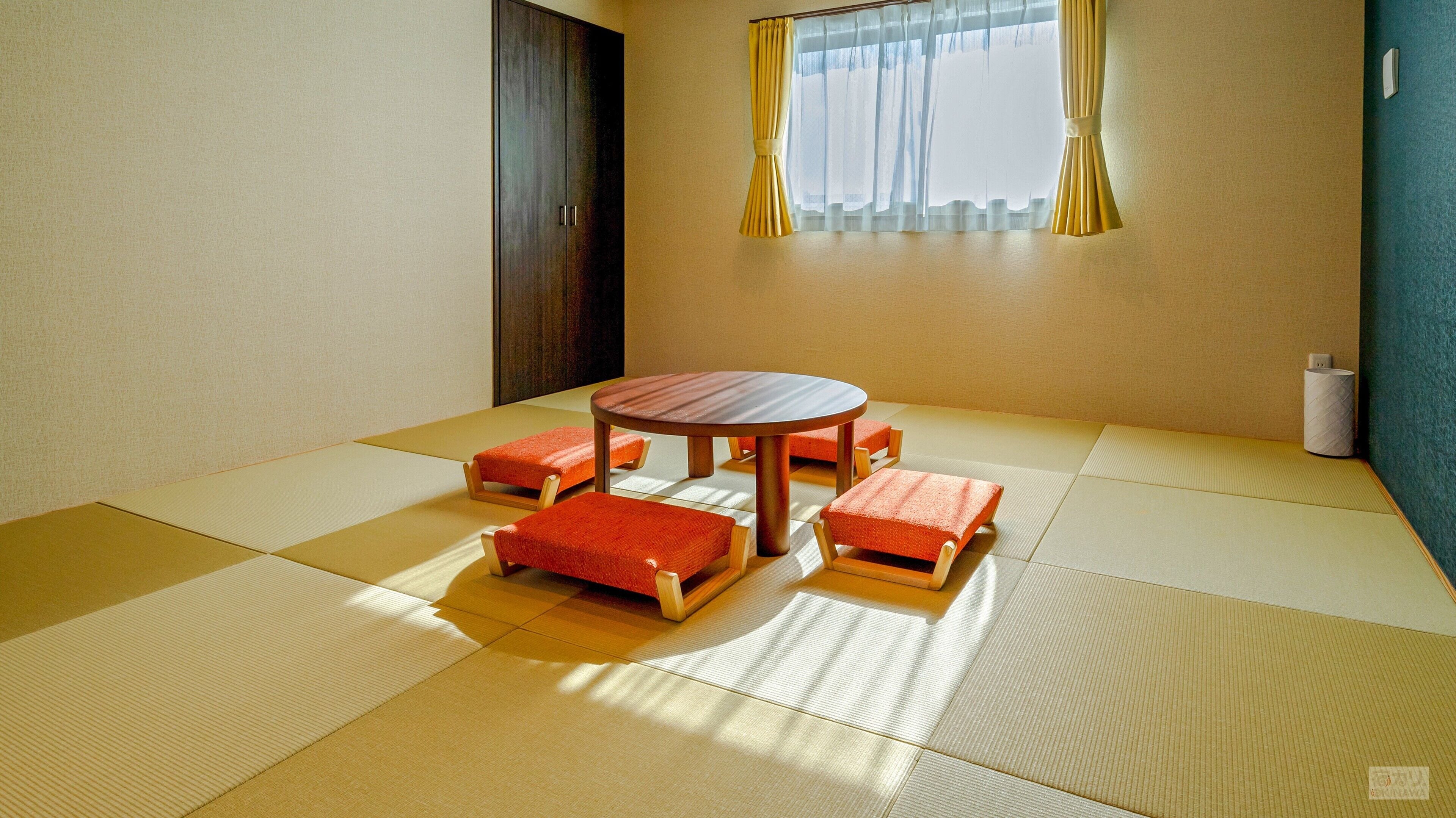 Una stanza con tatami, un tavolo rotondo e quattro panche abbinate.