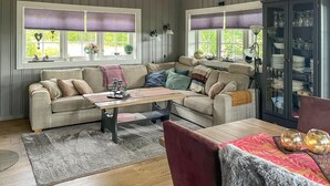 A cozy living room with a sofa, a coffee table, and a cabinet with glassware. - Amazing home in Rena with sauna (Rena)
