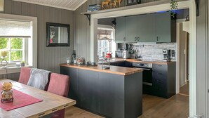 A modern kitchen with a central island, dark cabinets, and a wooden countertop. - Amazing home in Rena with sauna (Rena)