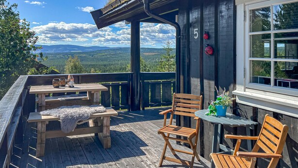 A wooden deck with a table and chairs, a potted plant, and a view of the landscape. - Amazing home in Rena with sauna (Rena)