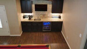 A modern kitchen with dark cabinets, a stone backsplash, and a built-in TV. - Quiet lakefront home. on Lake Leon, Eastland TX.  90 min to Fort Worth. (Eastland)